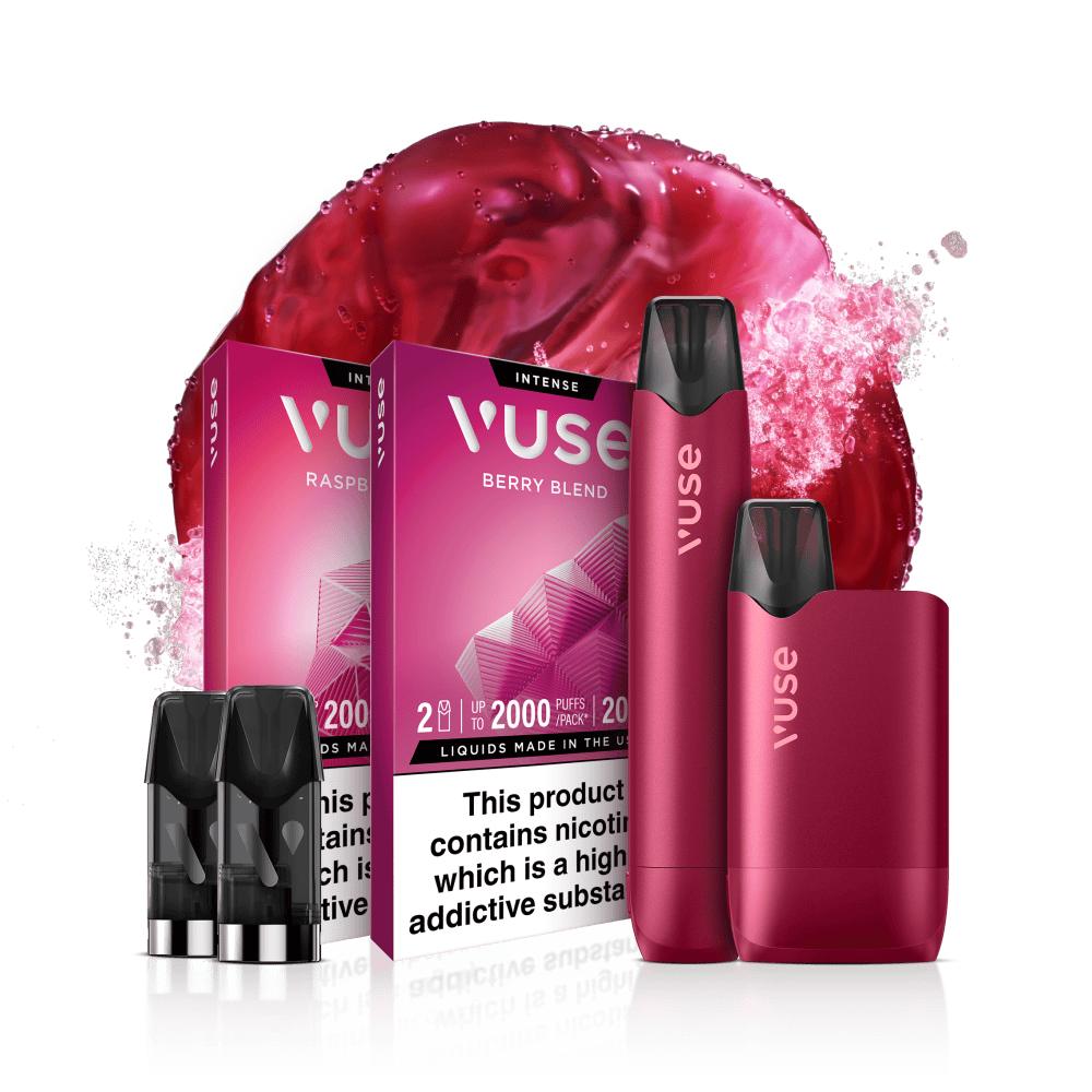 Two berry-colored Vuse vape devices, two vape pods, and two vape juice boxes labeled Raspberry and Berry Blend against a splash of red liquid backdrop. Warning text states the product contains nicotine.