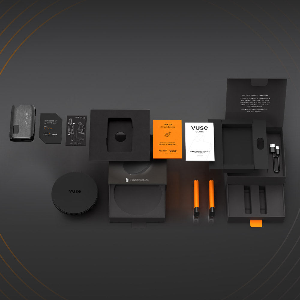A flat lay of the Vuse Ultra Device Kit McLaren by Vuse, featuring a black advanced vape, two orange vape pens, charging cable, instruction booklets, and packaging—all neatly arranged on a dark background.