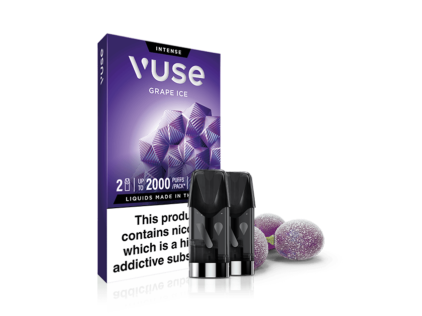 A Vuse Grape Ice vape pod pack with two pods is shown. The purple box features geometric grape designs, and two pods are in front. Several whole grapes with frosty coating are placed beside the box.