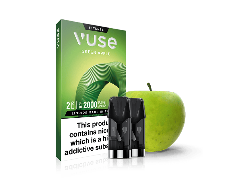 A Vuse Green Apple vape cartridge pack is shown with two vape pods in front and a fresh green apple in the background. The packaging notes 2 pods, 2000 puffs per pack, and contains a nicotine warning.