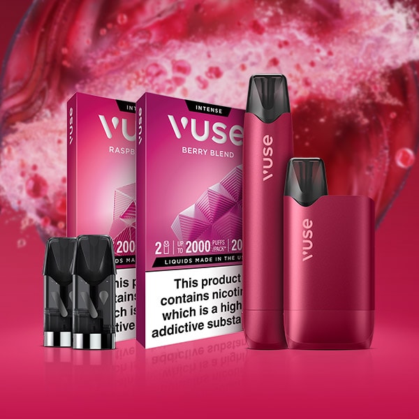 Two Vuse vape devices in metallic pink stand in front of Berry Blend and Raspberry flavored e-liquid boxes, with vape pods displayed beside them. A vibrant berry splash forms the background.